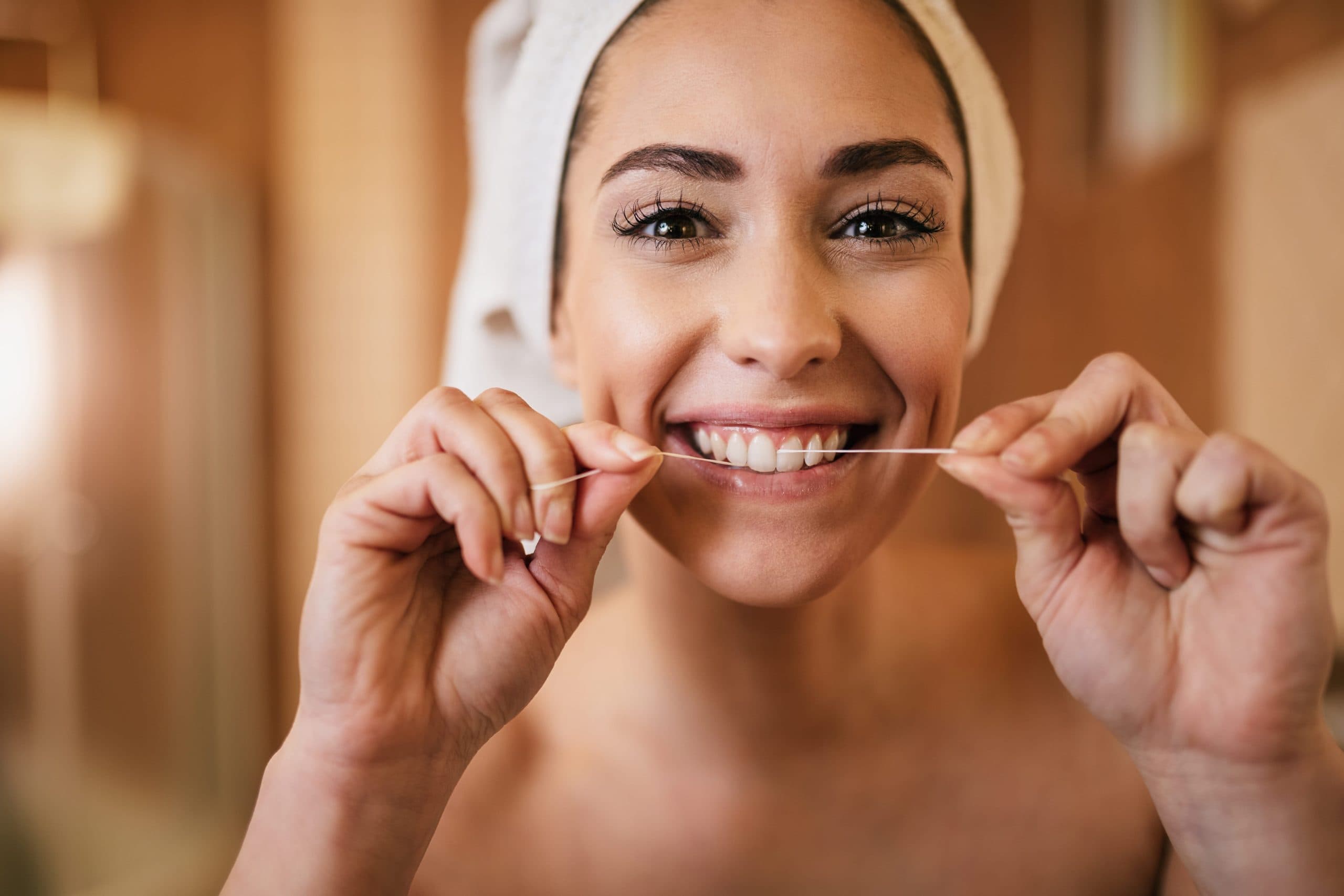 Mujer utilizando hilo dental como parte de su higiene bucodental